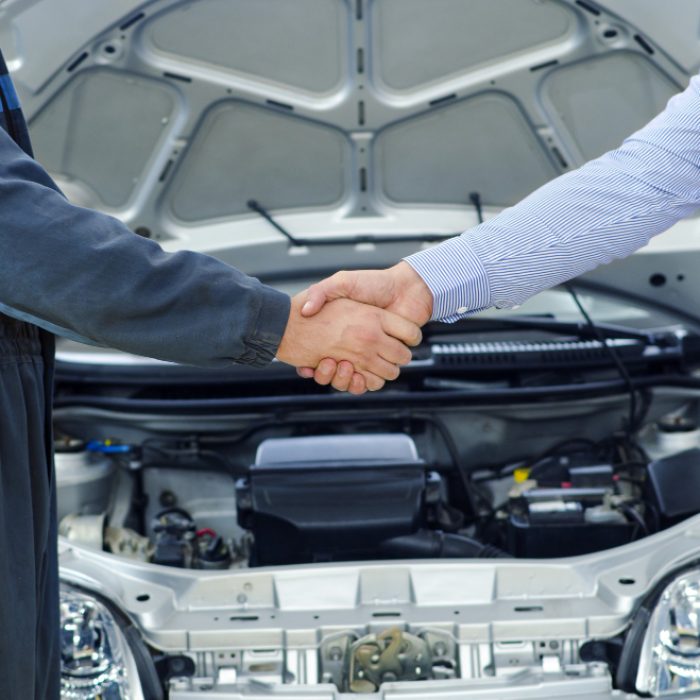 Car owner and auto mechanic shaking hands in a professional repair shop